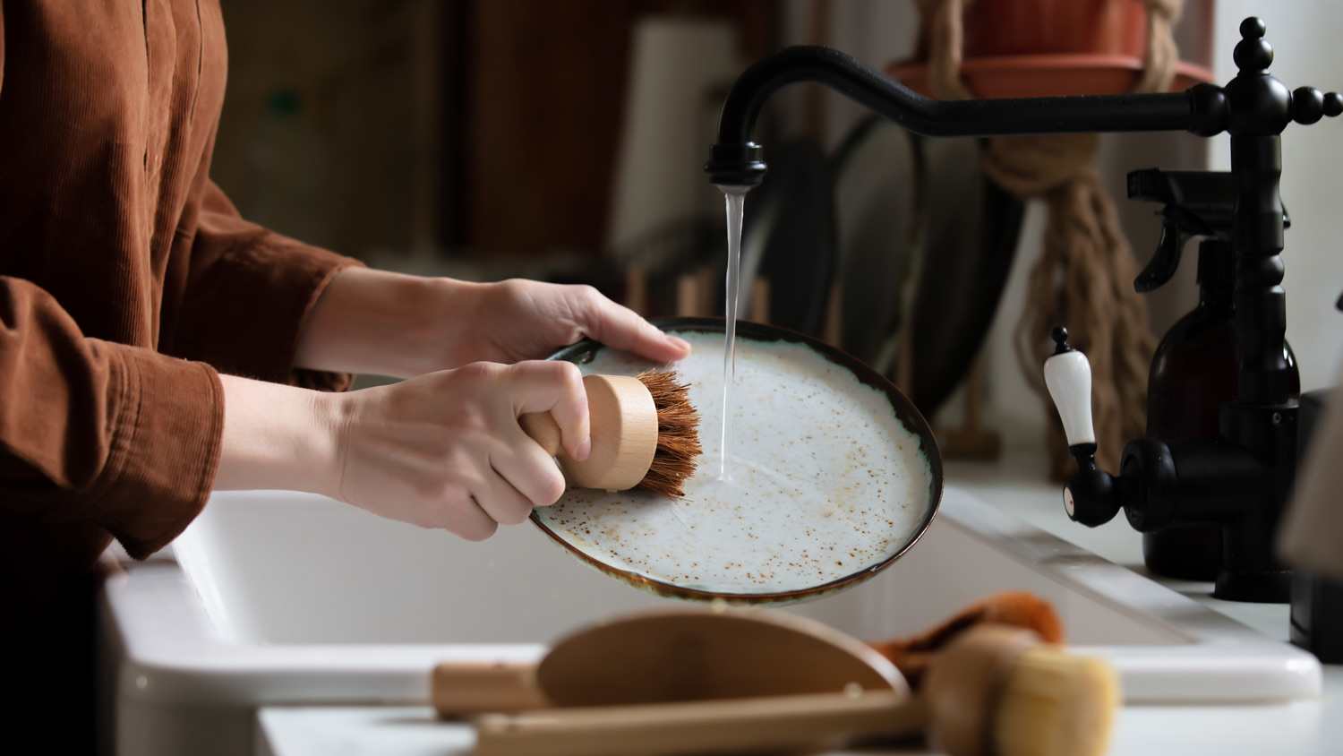 A woman rinsing a plate in sink