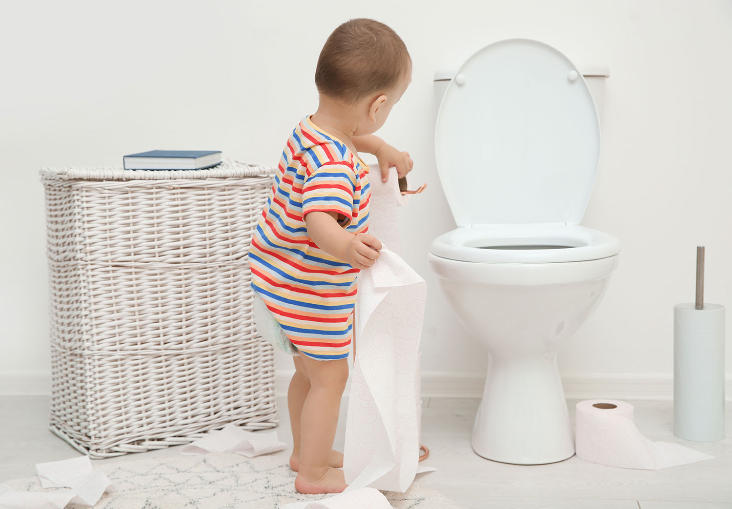Toddler playing with toilet paper in the bathroom