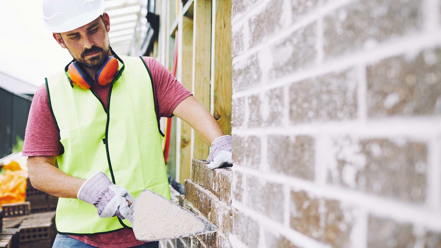 A worker checking on a brick wall of a construction site