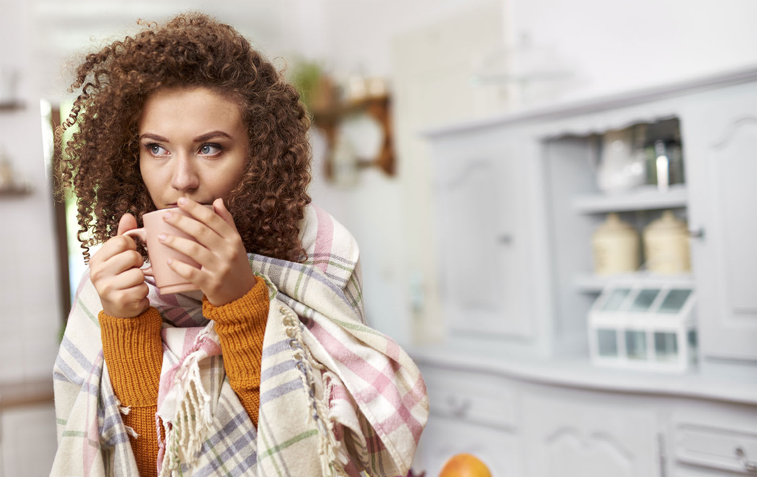 Woman wrapped in a blanket drinking hot tea