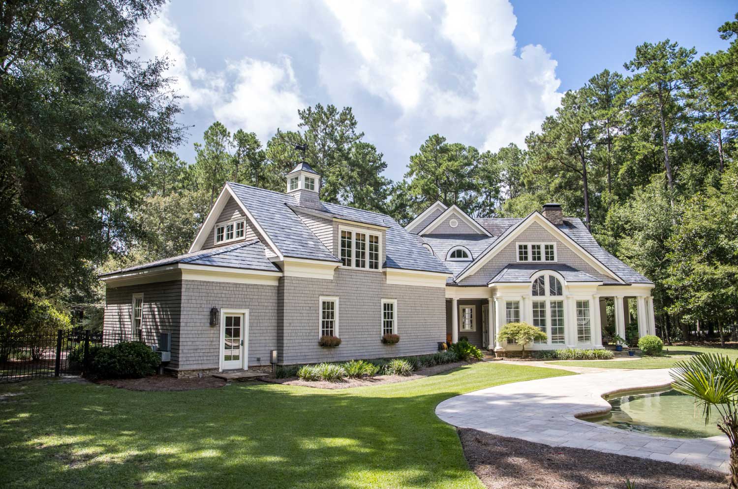 A large gray house with wood shingle and a chimne