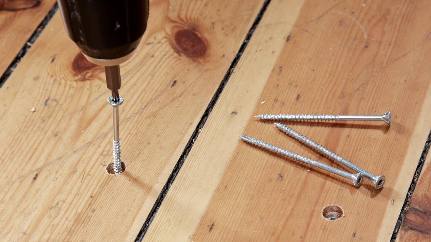 Repairing a squeaking floor by screwing floorboards down