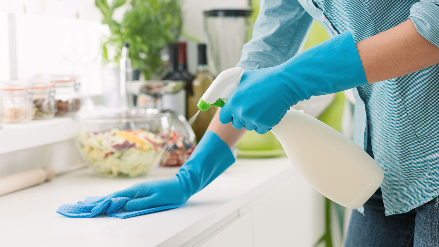 Close-up of a hand in glove spraying detergent on a surface