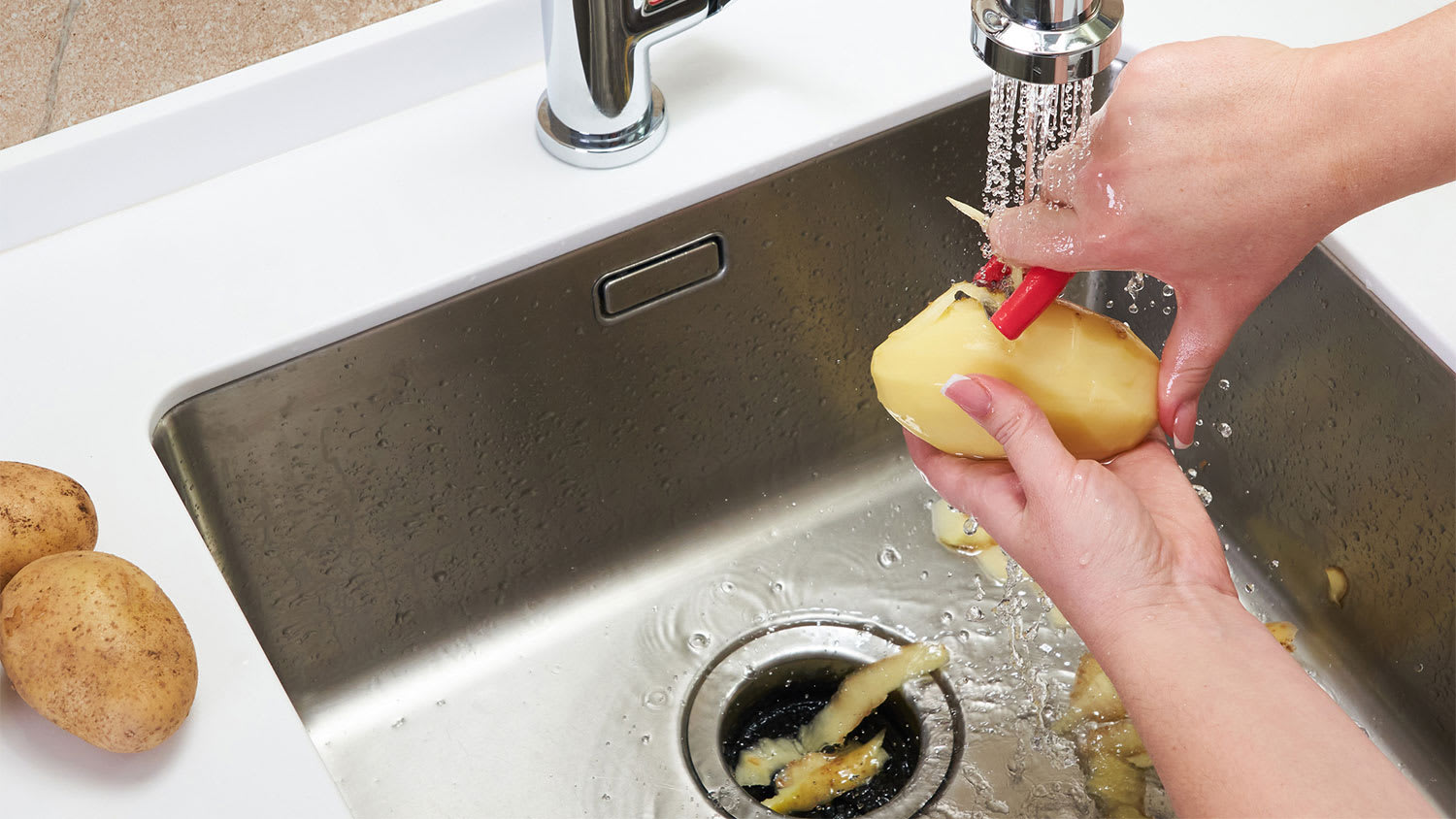 cropped view of woman peeling potatoes in kitchen sink