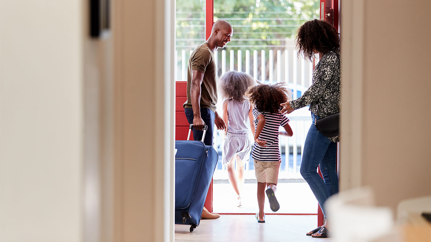 Family walking out the front door with a suitcase