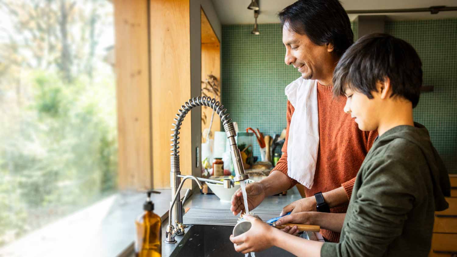 Father and son washing dishes in kitchen