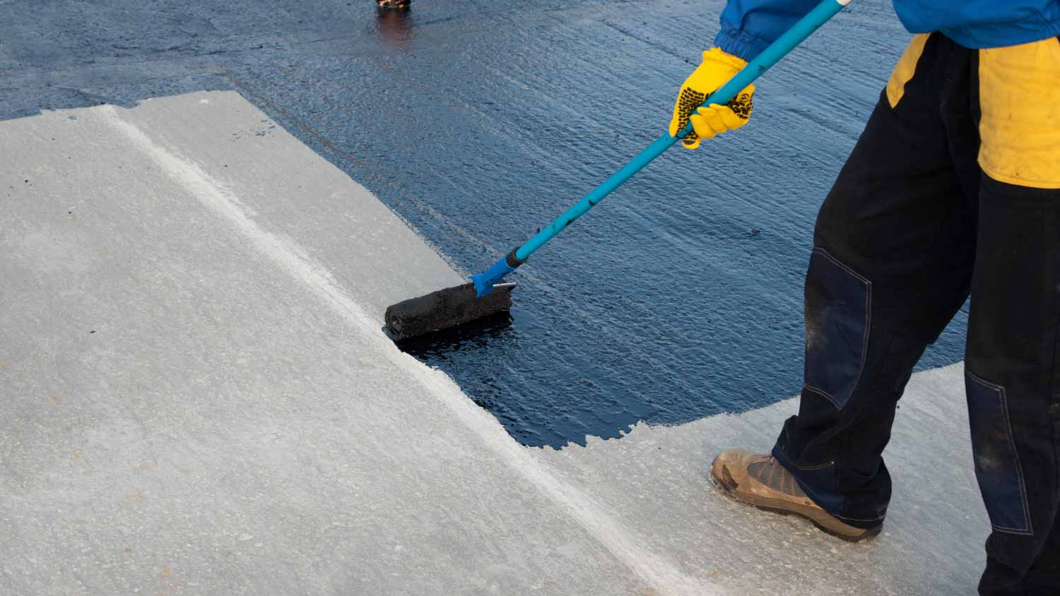 None Worker applying bitumen mastic