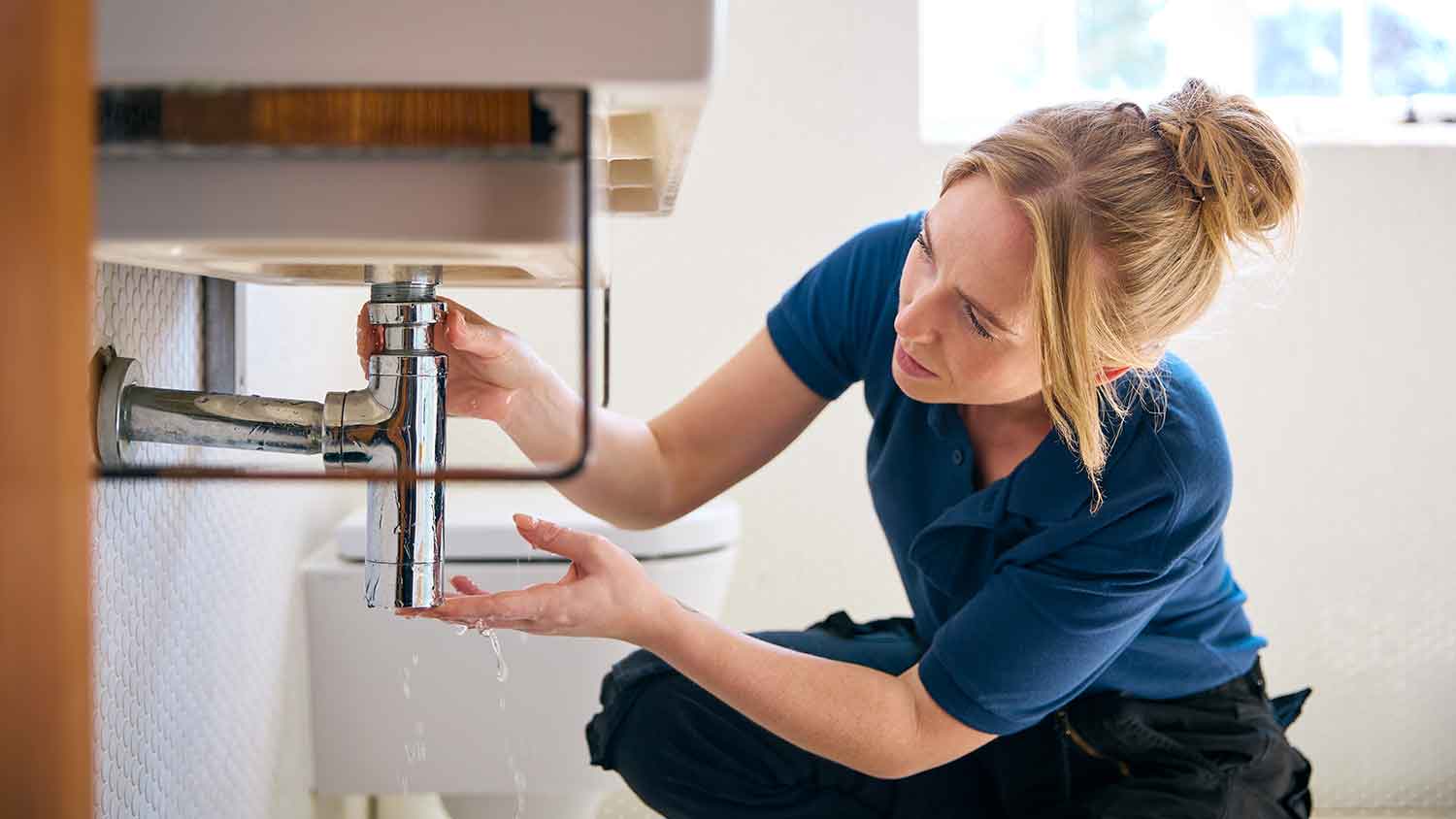 None Female plumber fixing bathroom sink pipe