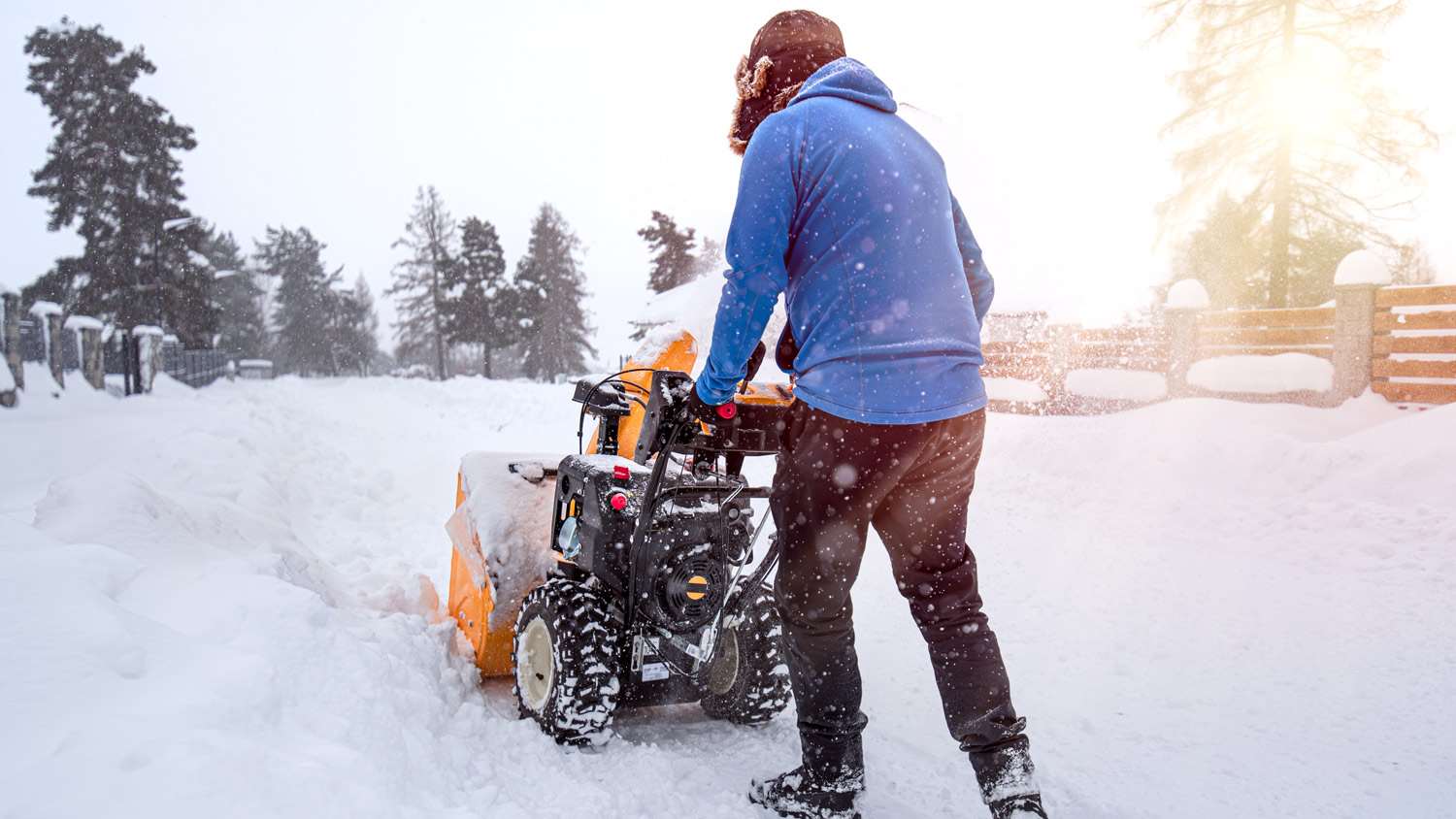 Man with yellow The snow-covered snowblower