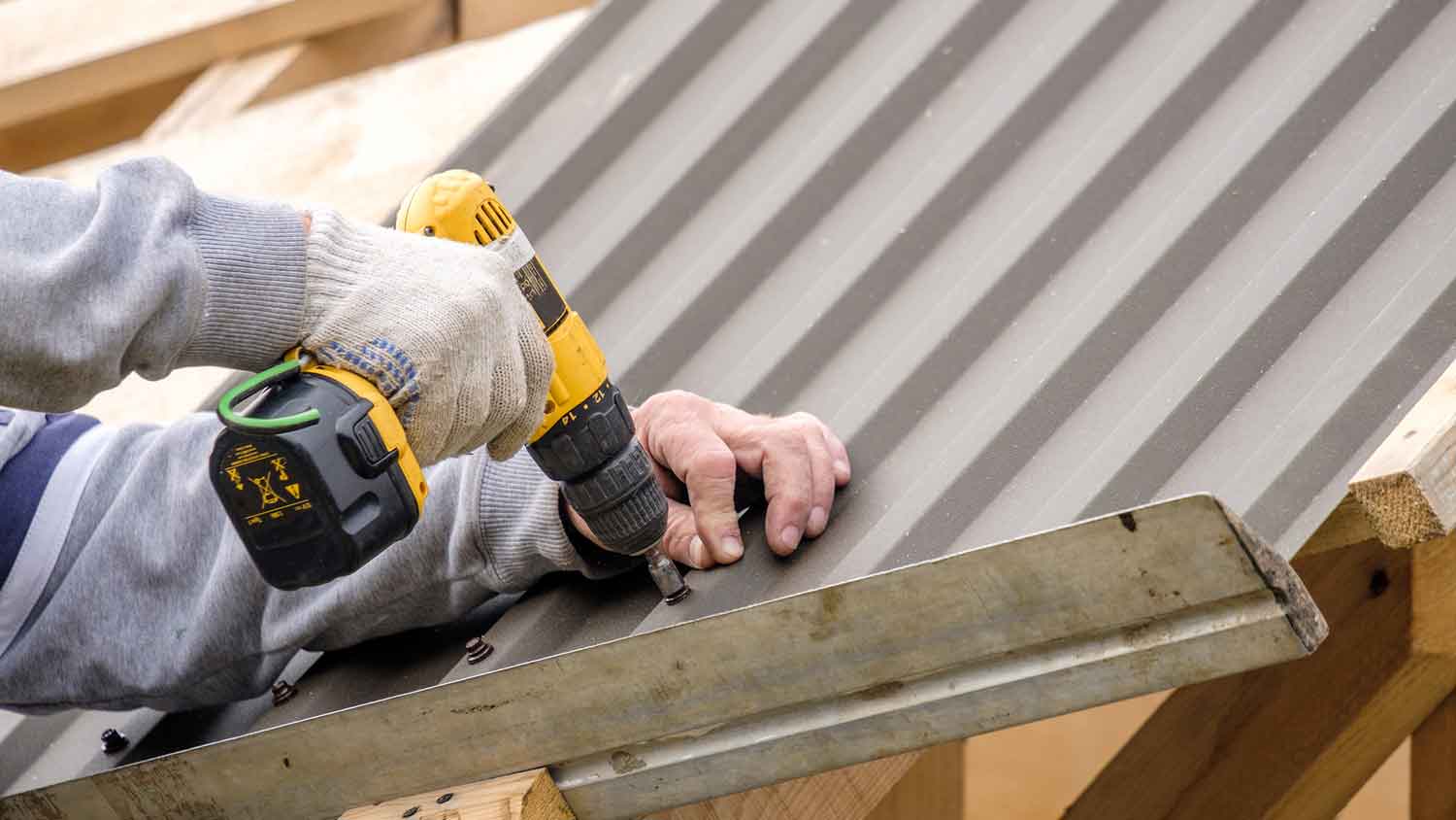 None Roof professional using screwdriver to install tin roof