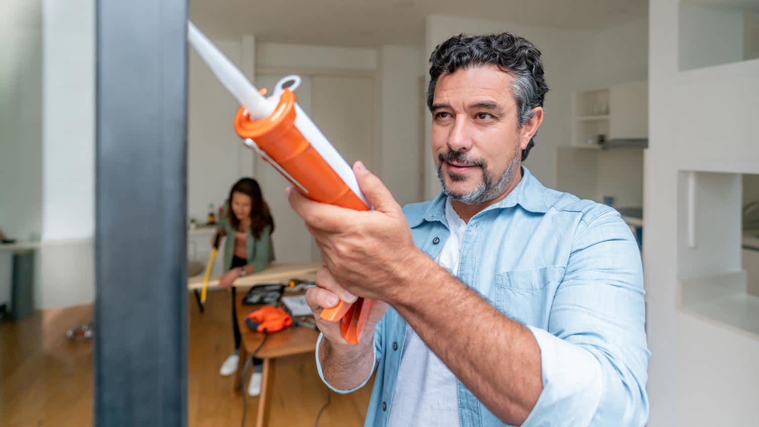 man using caulk on his door