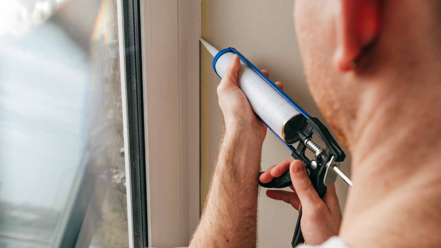 None Worker sealing cracks between window and trim