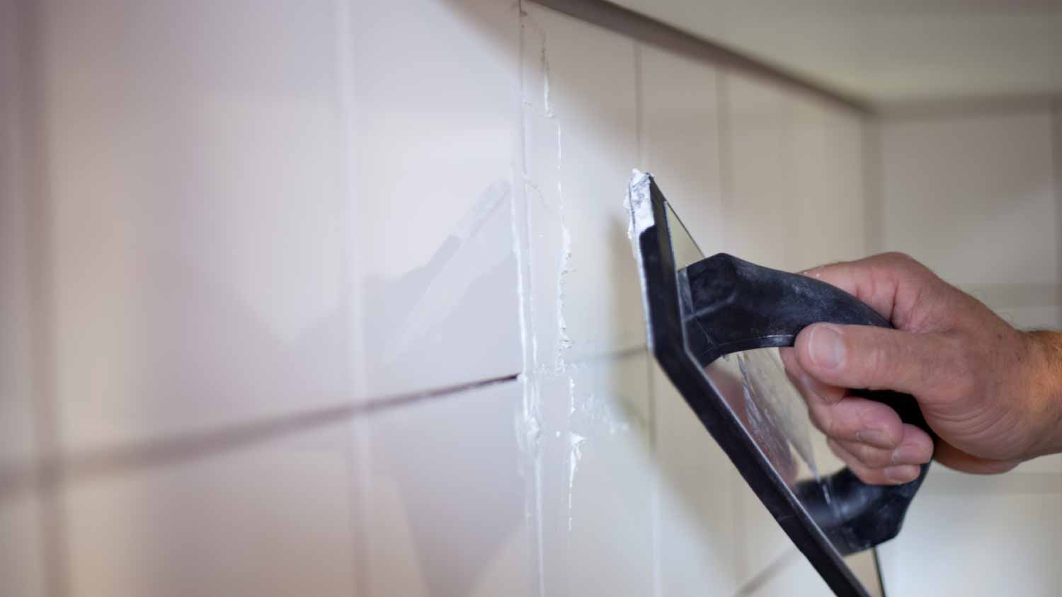 None Worker applying grout to the white wall