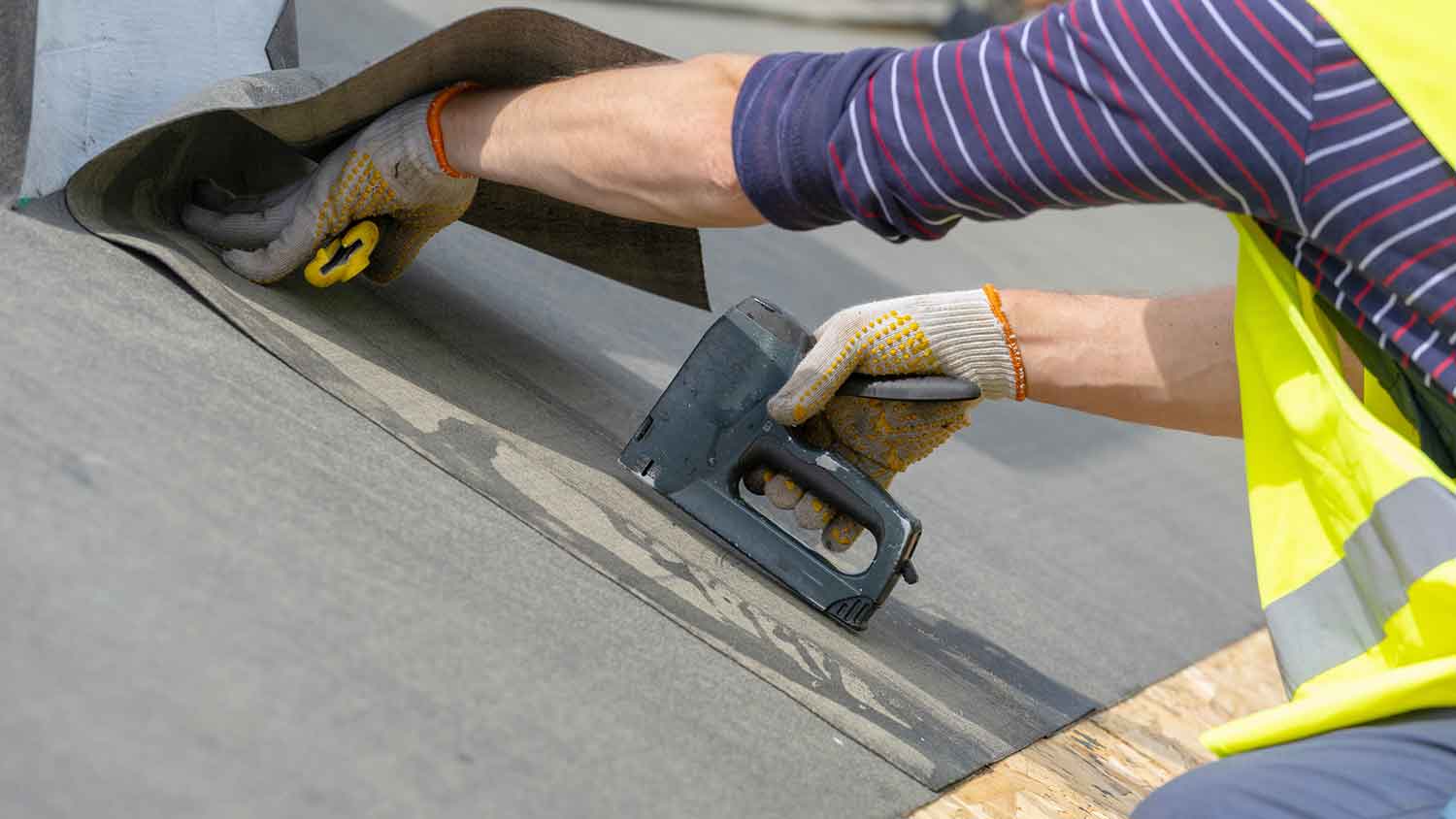 None Worker using stapler to install roof underlayment