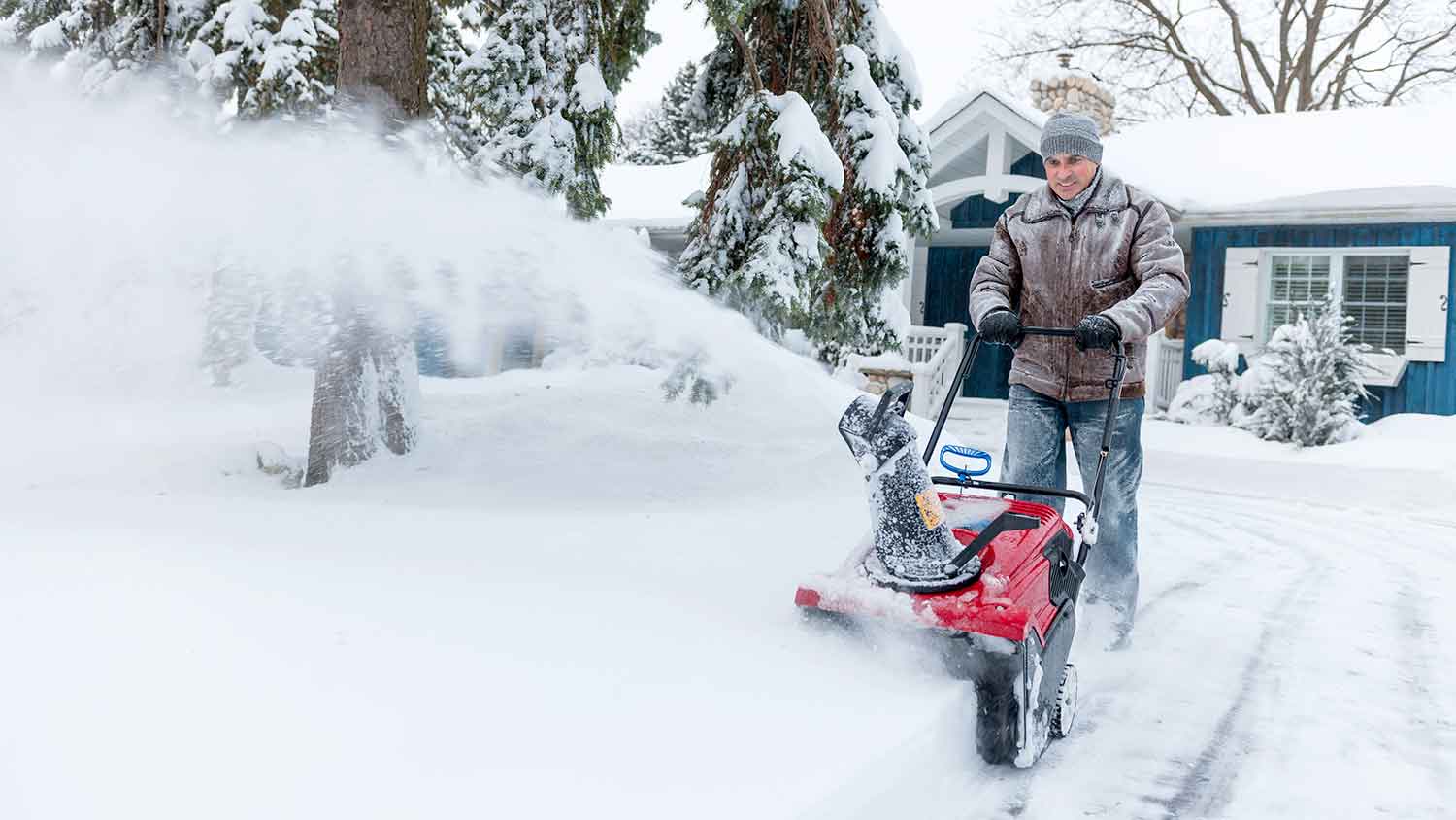 Man using snow blower to clear snow in the driveway