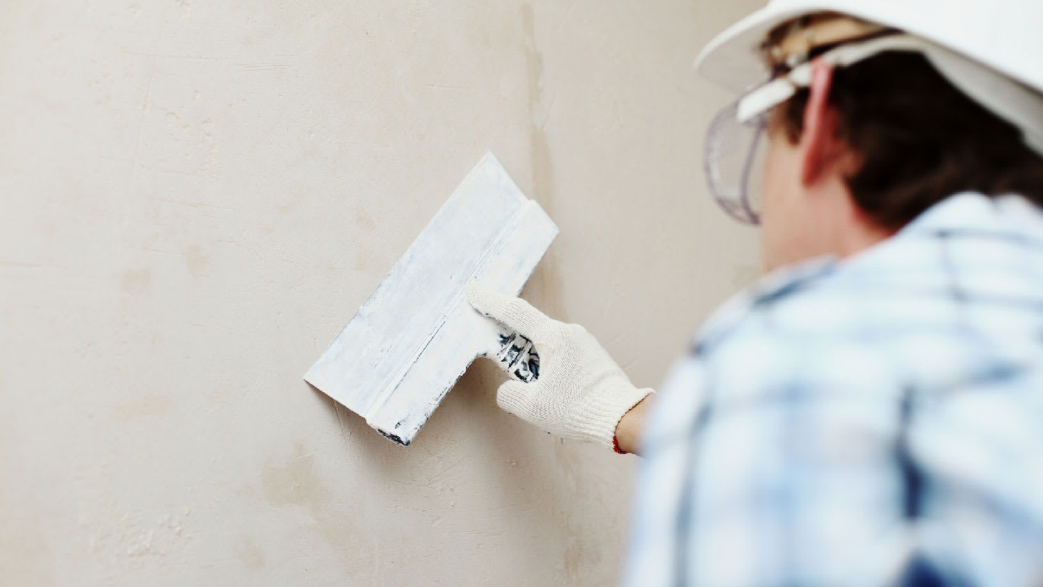 A person repairing stucco with a spatula