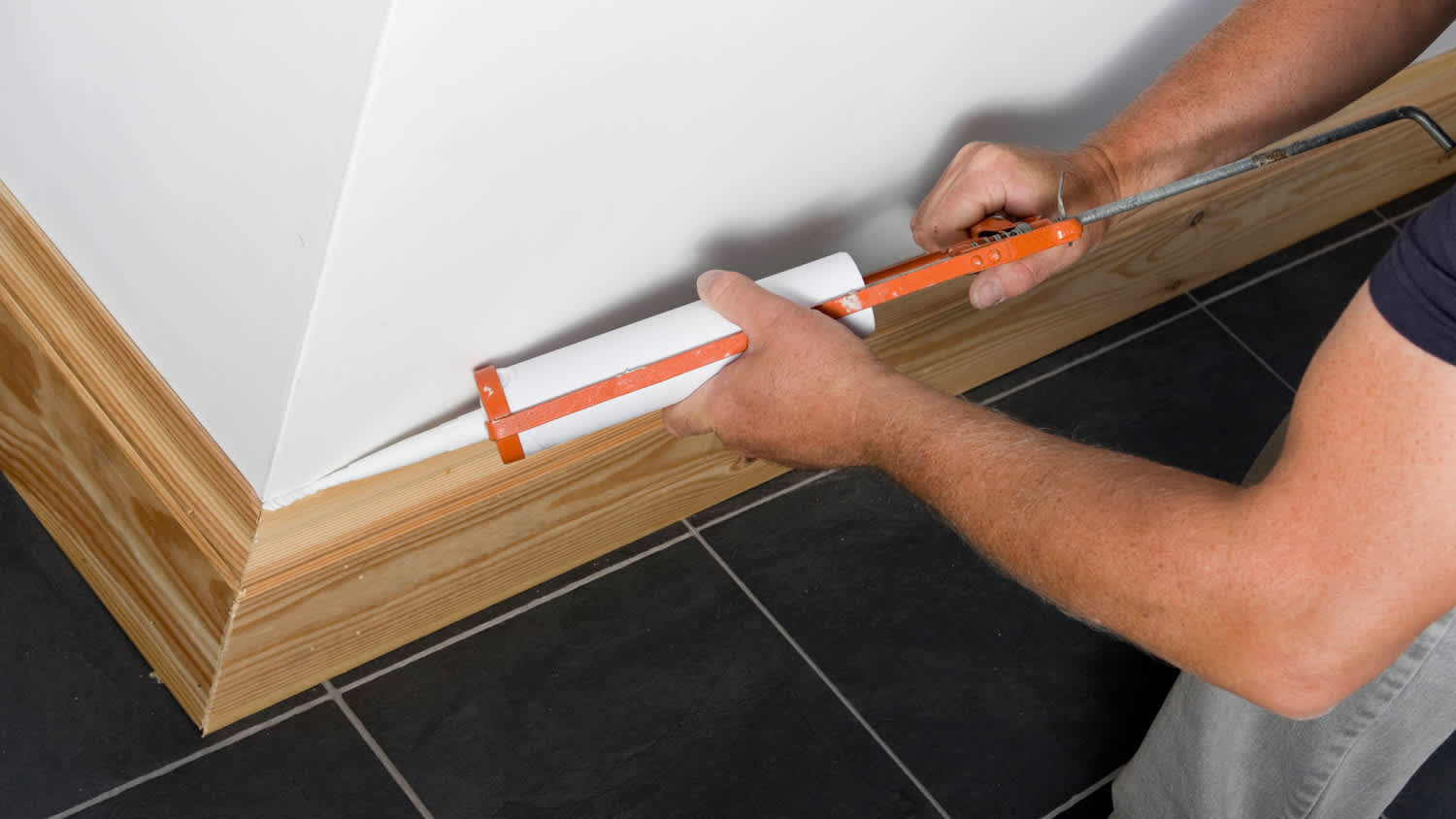 None Man caulking wooden skirting in a new property