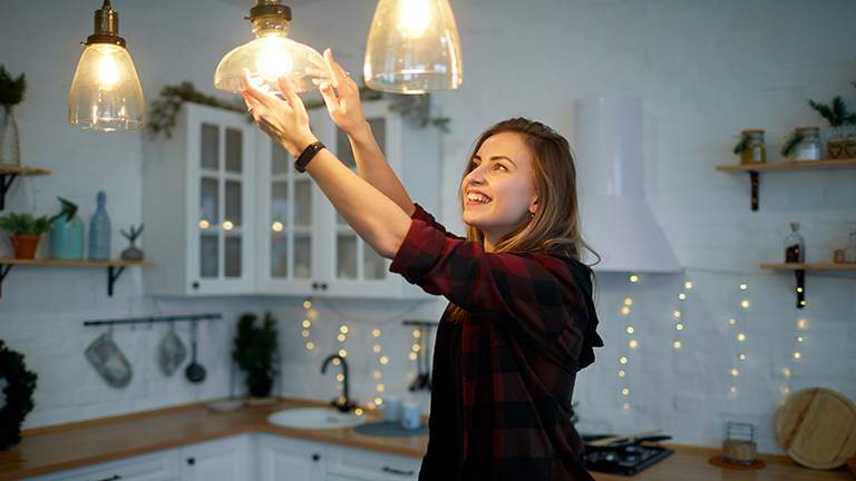 Woman screws in bulb on hanging light