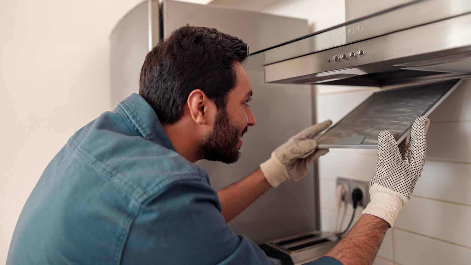 Worker repairing kitchen extractor
