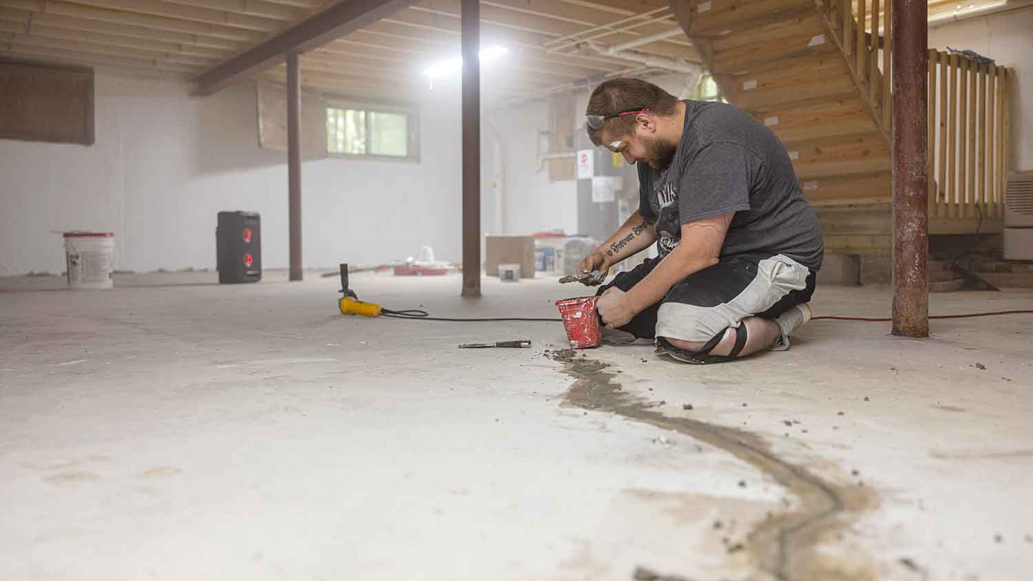 None Worker sealing basement floor cracks