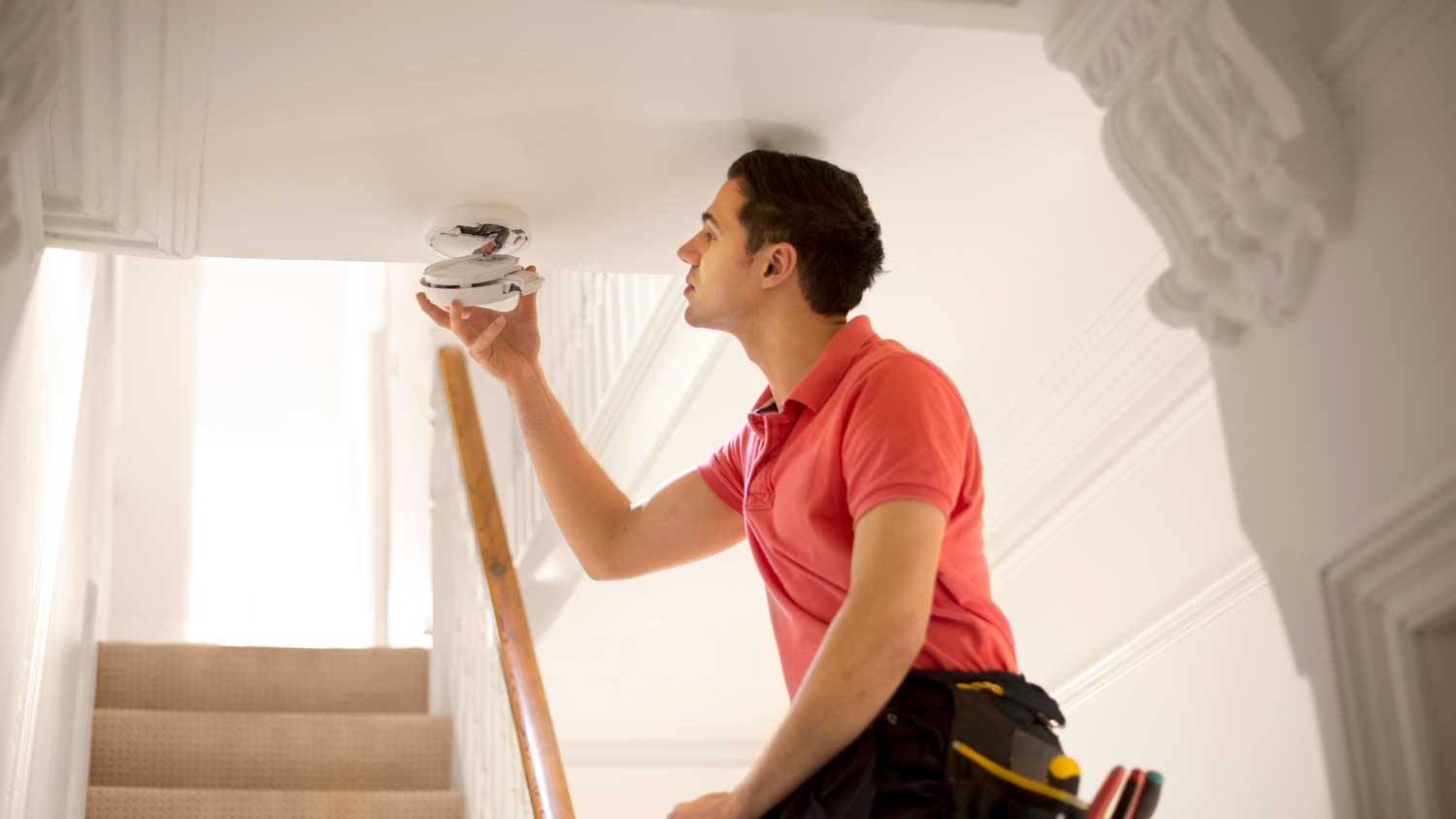 Handyperson installing smoke detector in a house