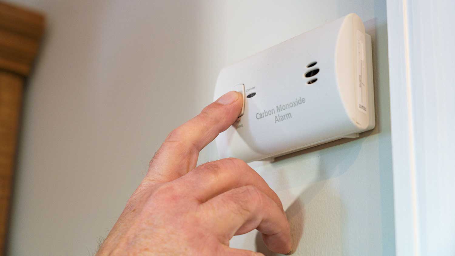 None Hand pressing test button on a carbon monoxide detector