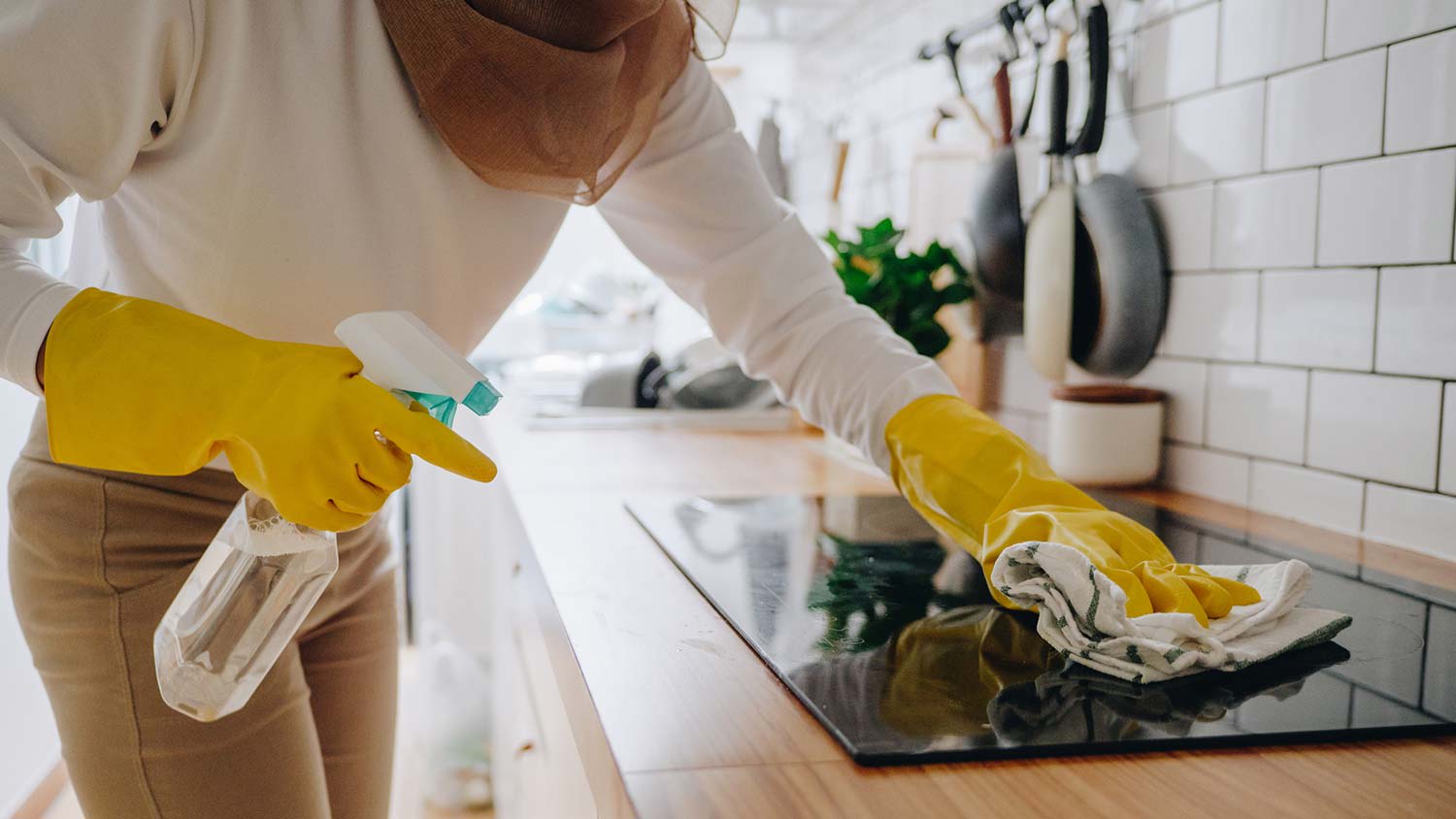 None A woman cleaning a glass stove top