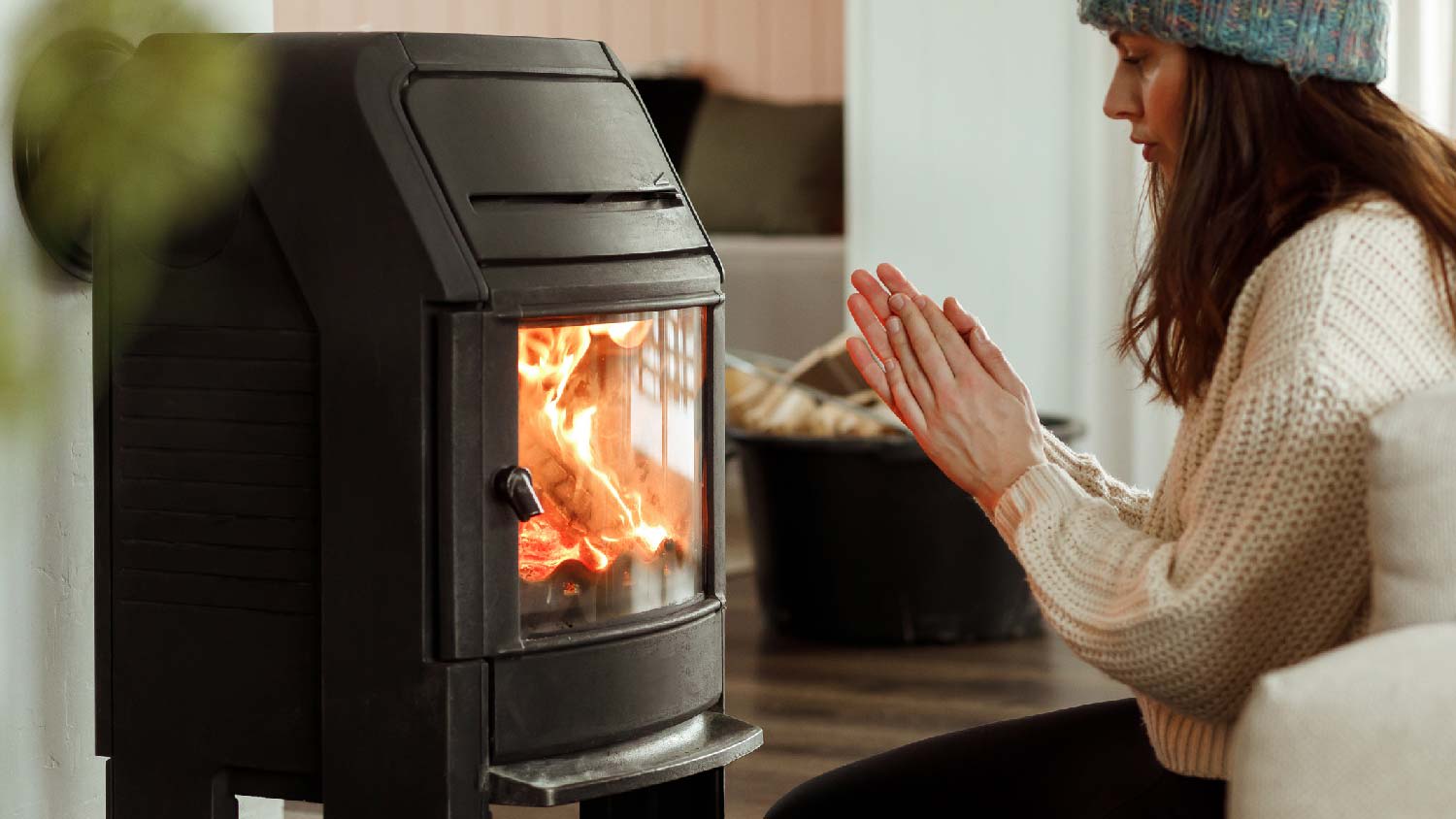 A woman sitting in front of a steel wood stove
