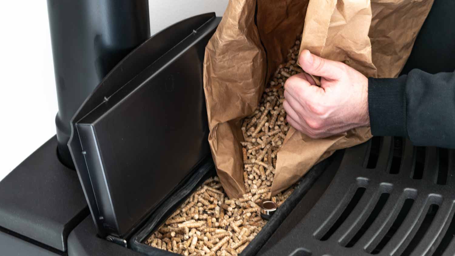 None Man loading pellet stove with granule bag