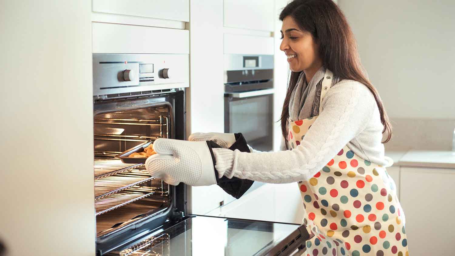 Woman taking baking sheet out of the oven