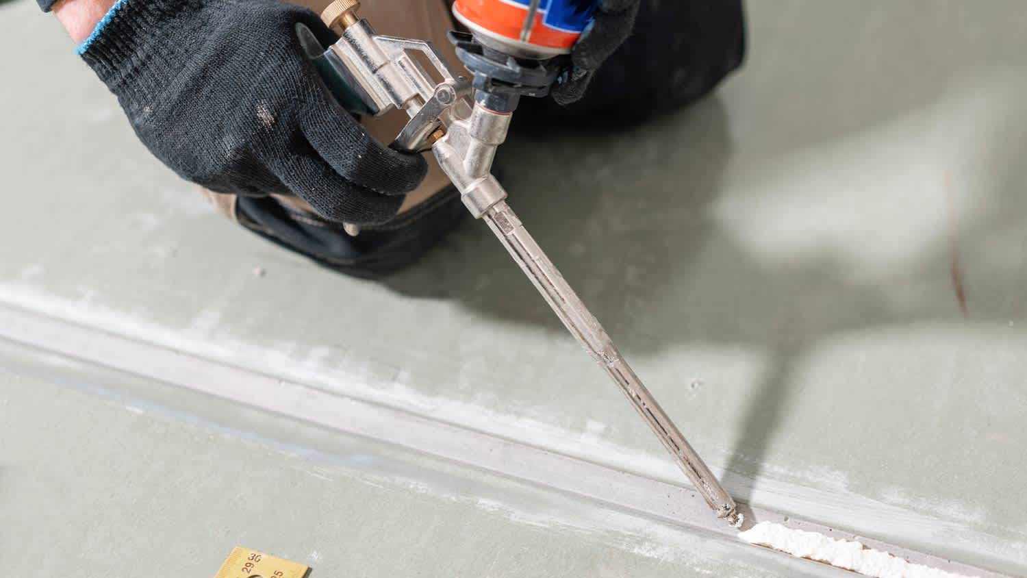 None man holding glue gun applicator for drywall
