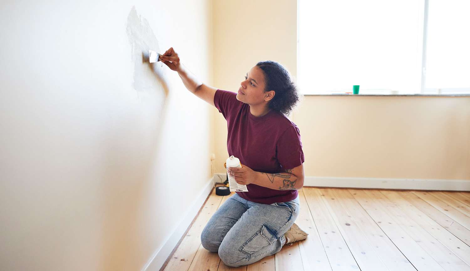 Woman putties at crack in wall