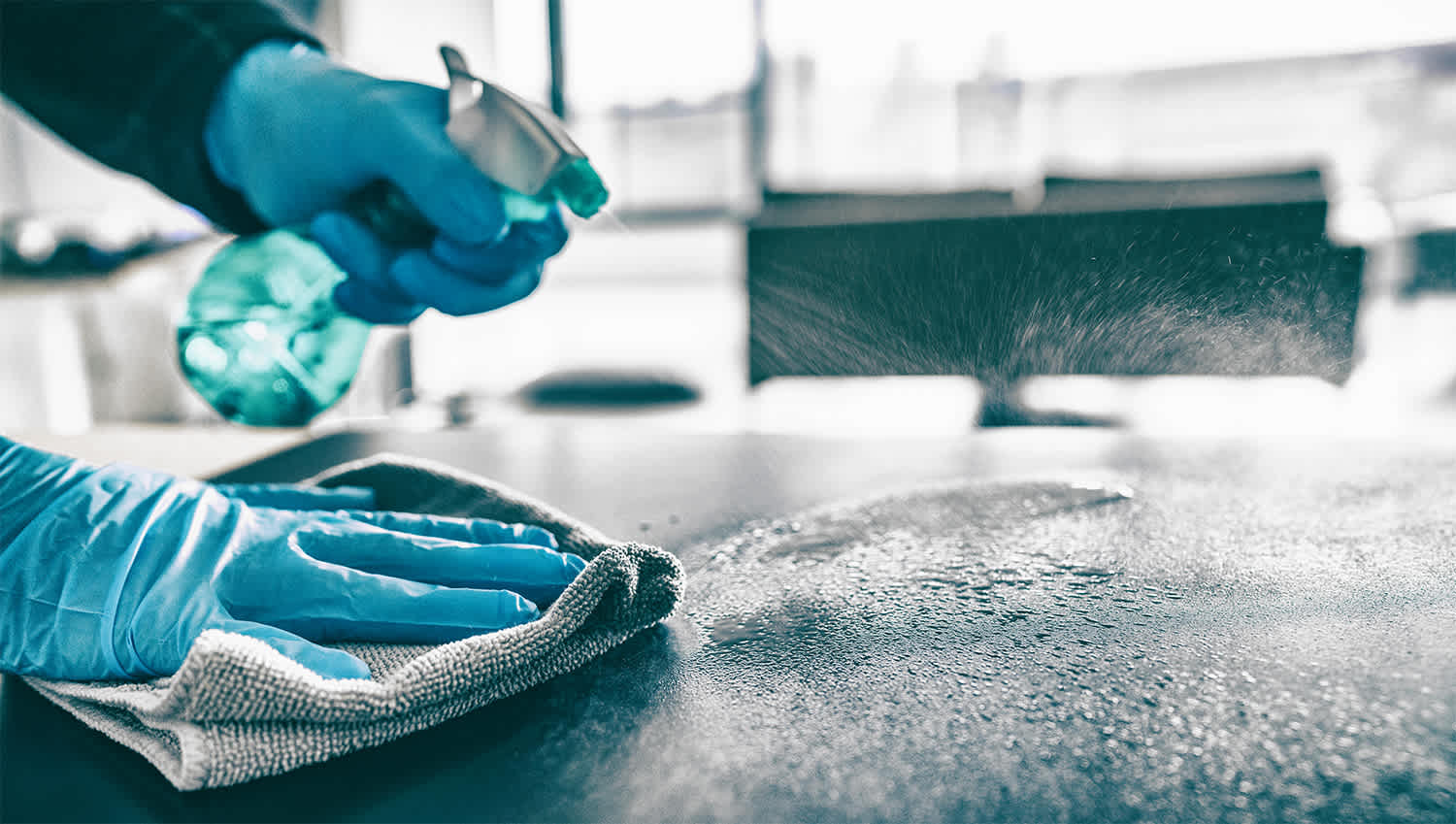 Person cleaning table with cloth and cleaner