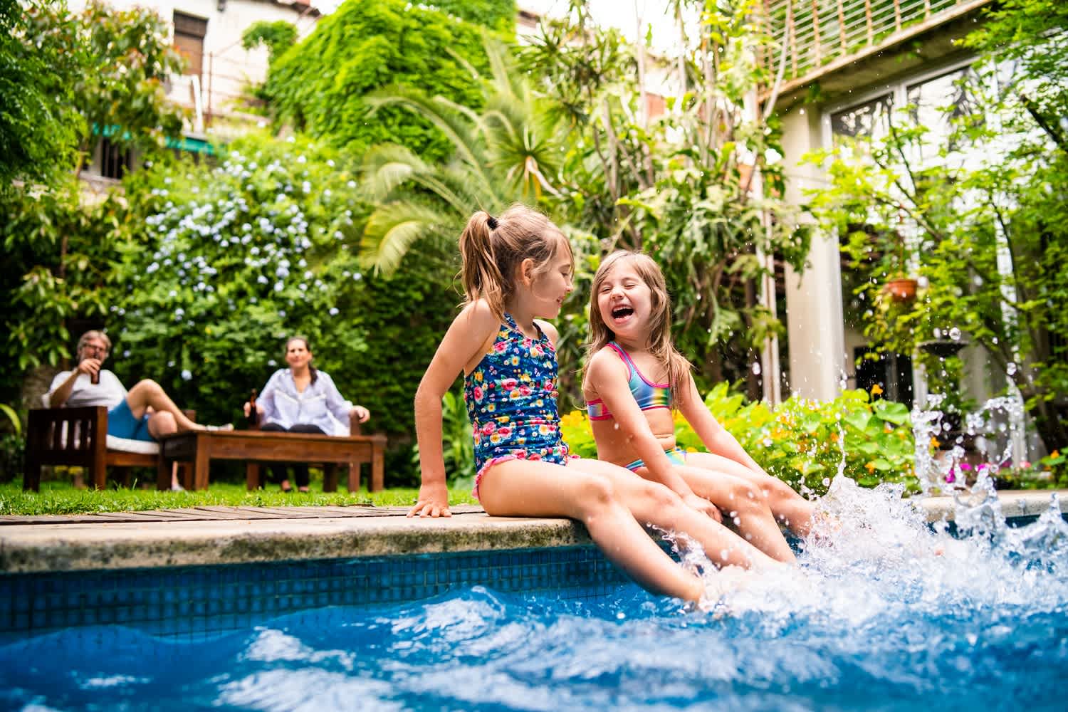 Family in backyard with children playing in the pool