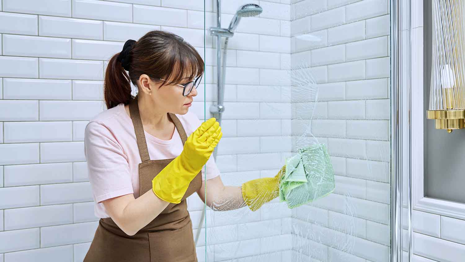 None Woman cleaning shower glass door