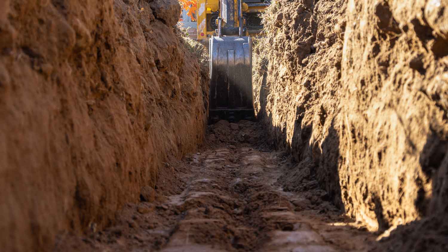 None An excavator digging a drainage trench