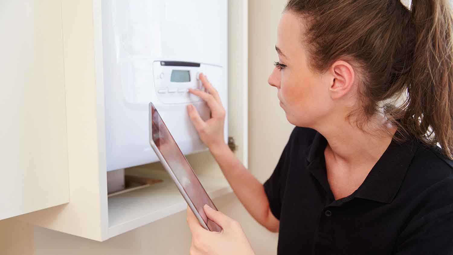Inspector holding a tablet is checking water heater temperature