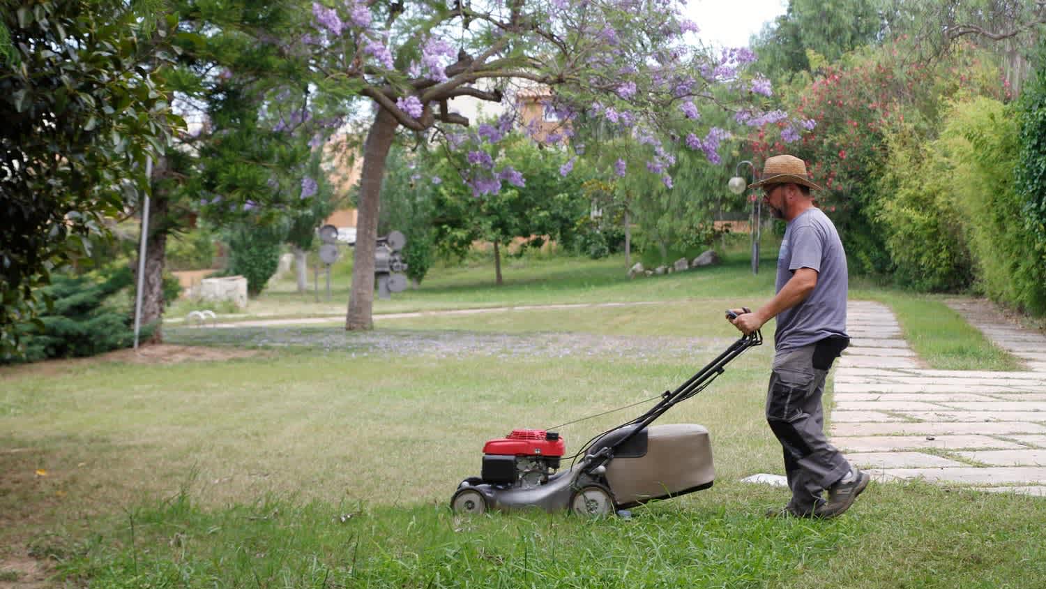 None A man mowing the grass with a lawn mower