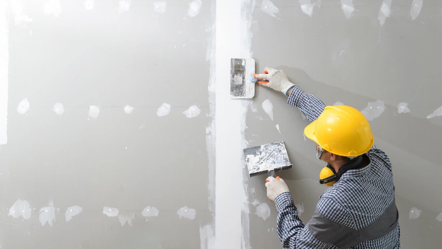A person plastering a drywall