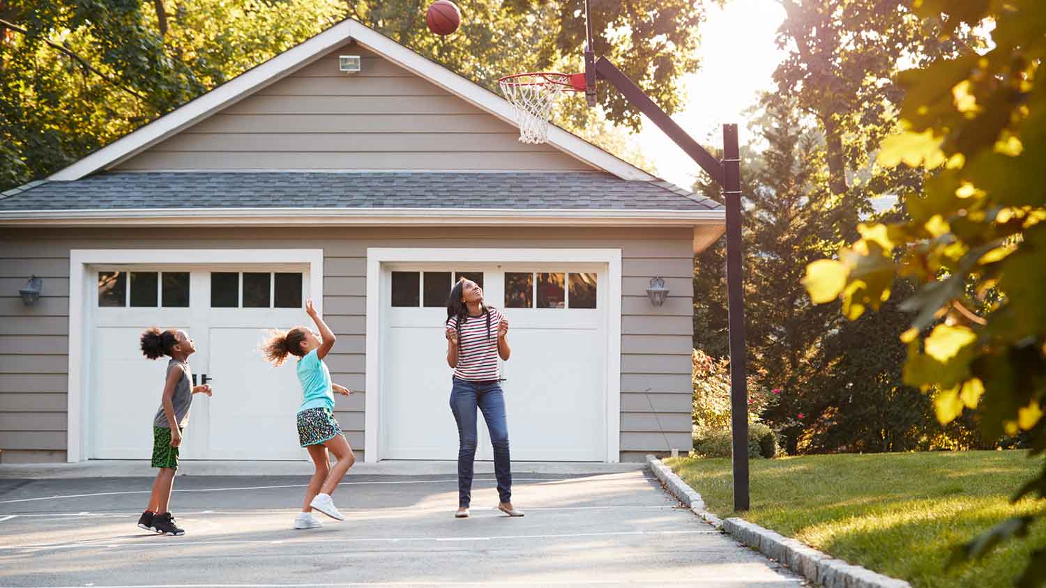 None Mother and children playing basketball in the driveway
