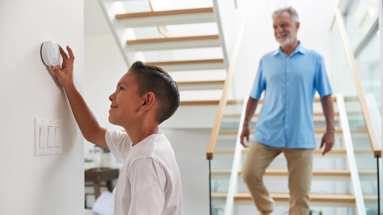None Grandfather With Grandson Adjusting Digital Central Heating Thermostat In Home