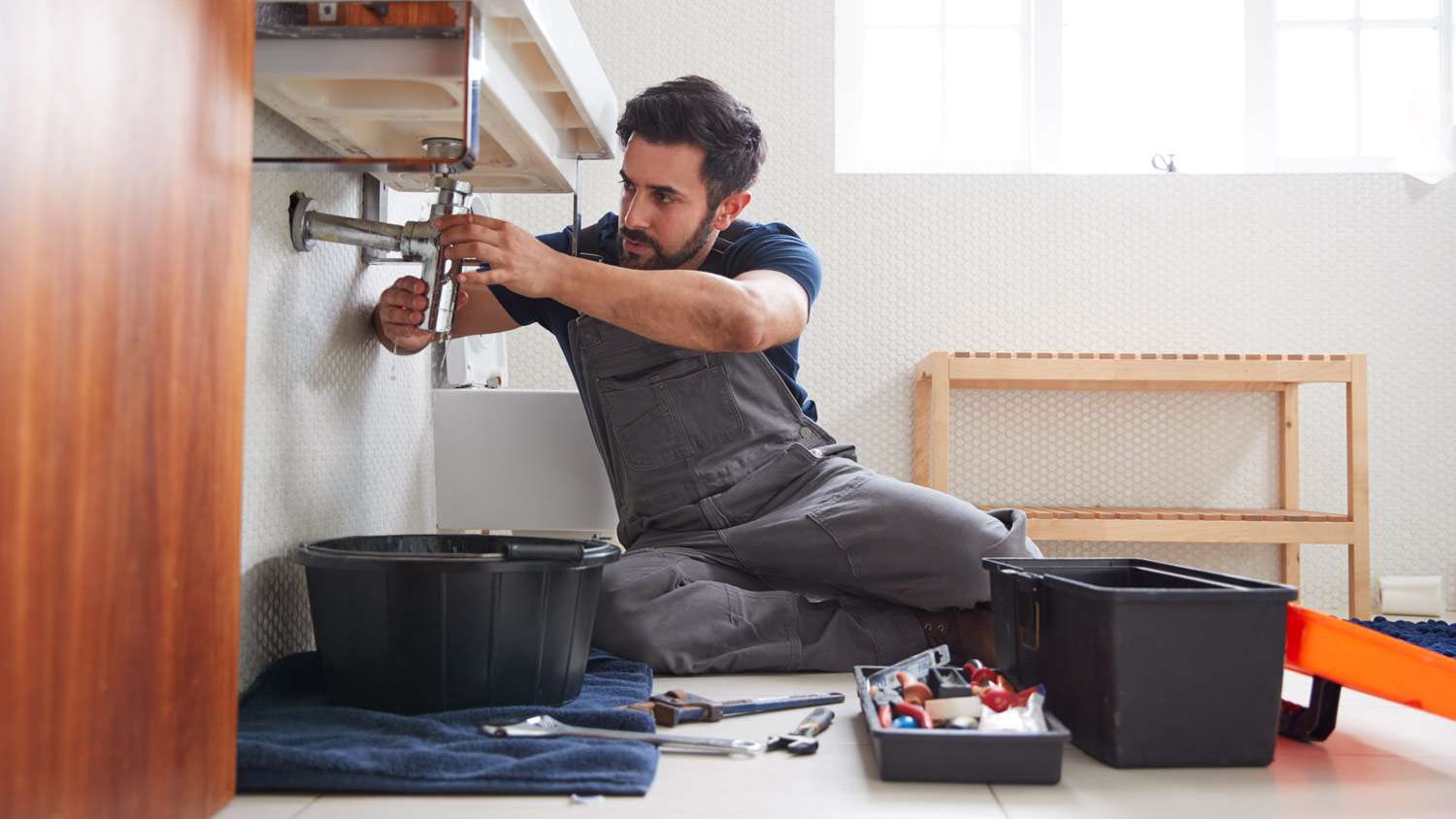 None A plumber installing a water pipe in bathroom