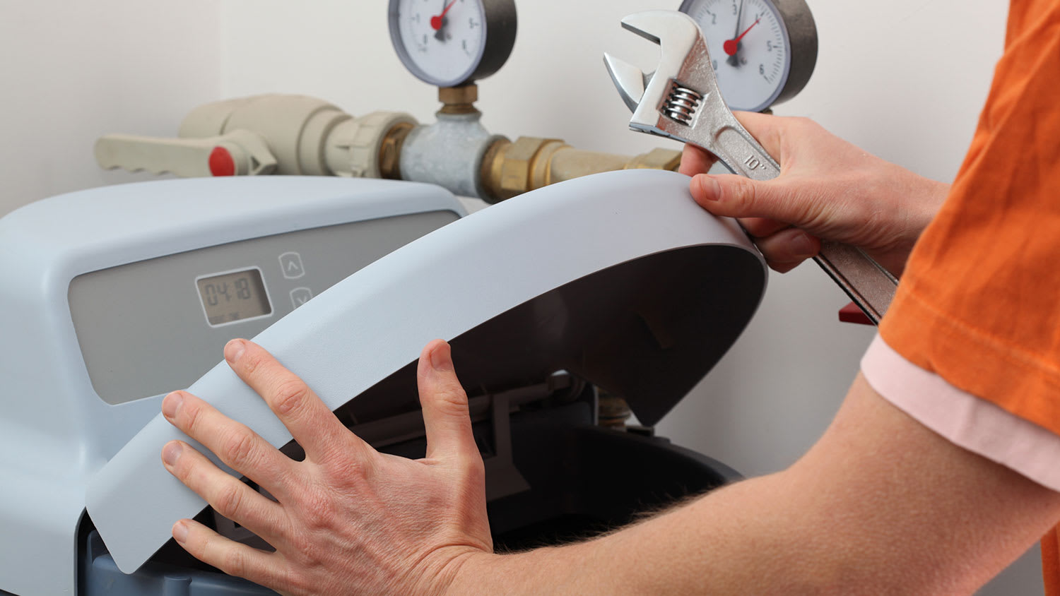 None Plumber repairing a water softener with a wrench