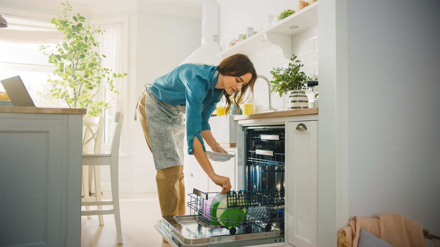 None A woman putting dished in the dishwasher