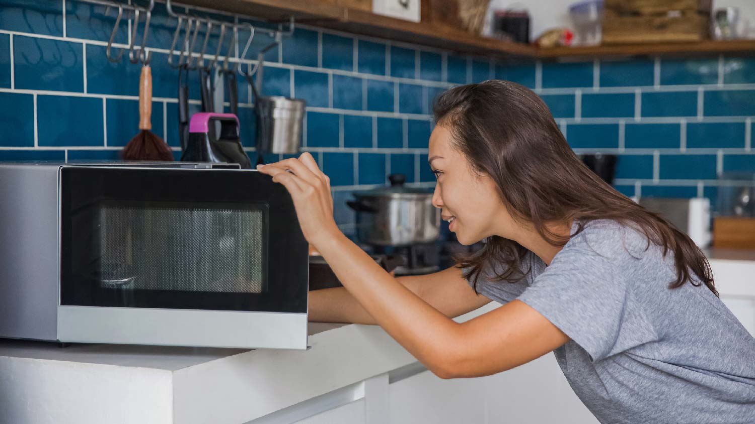 A woman taking food out of the microwave