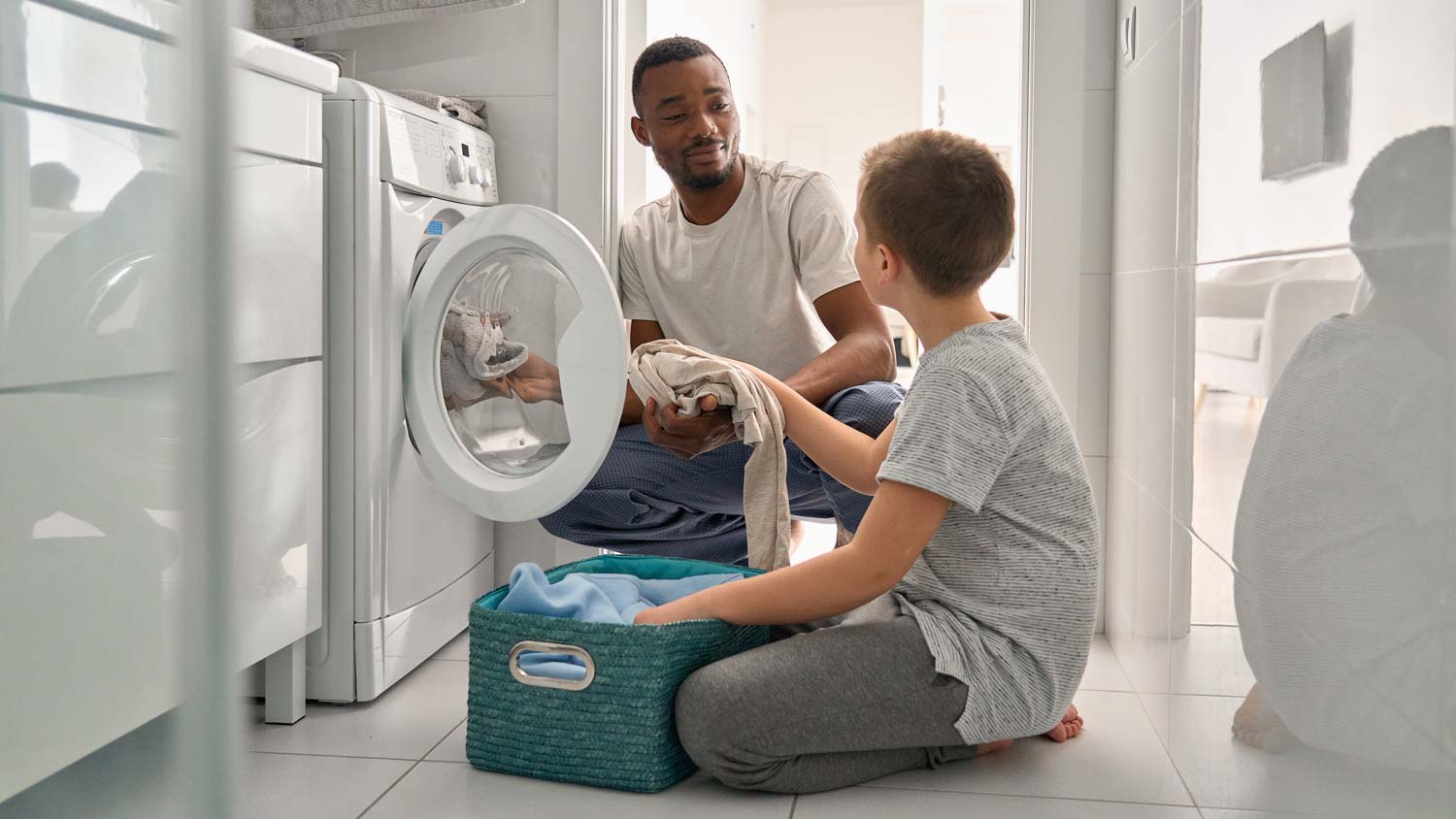 A father and his son loading the washing machine with clothes