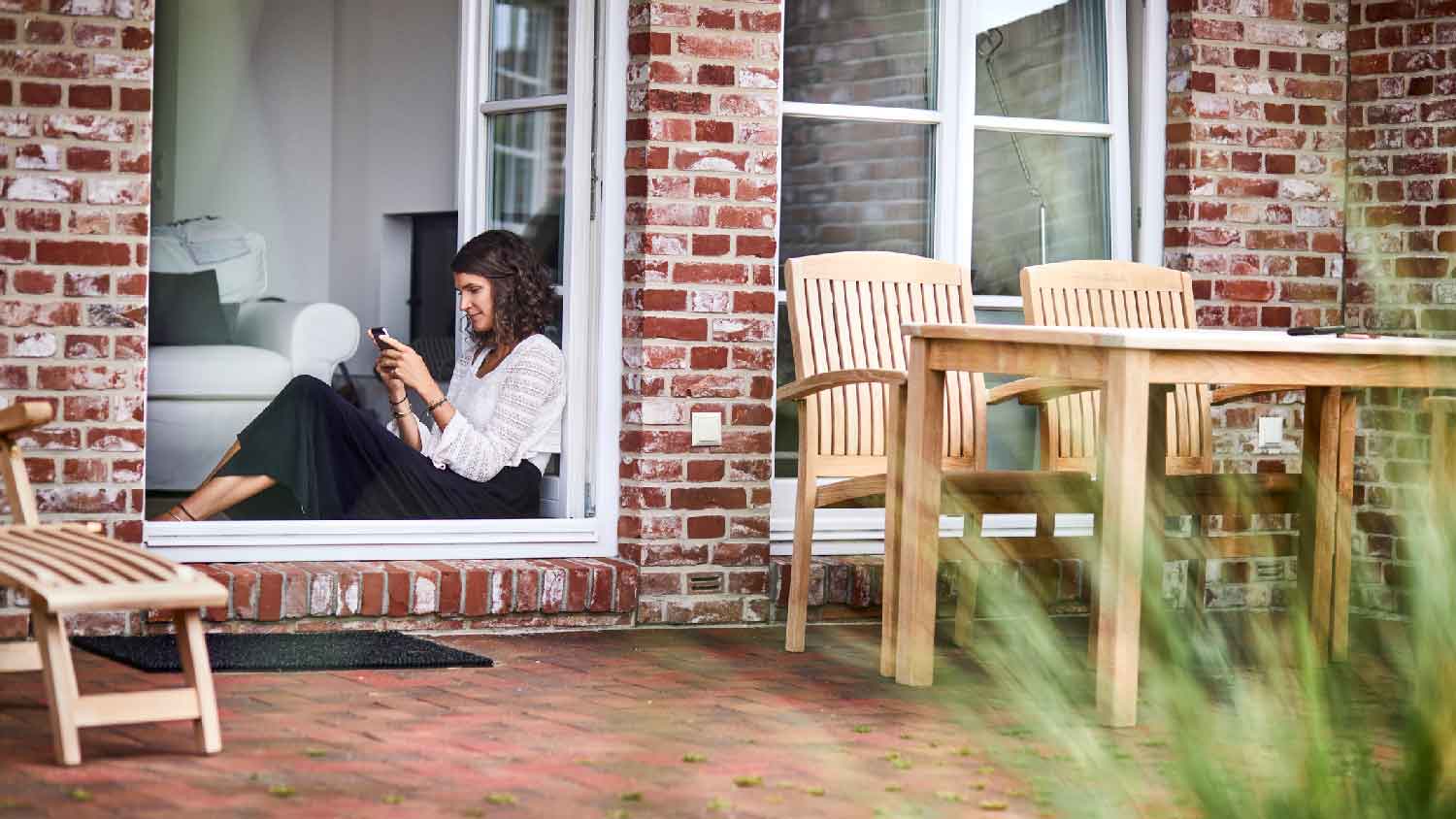 A woman checking her phone while in a brick house