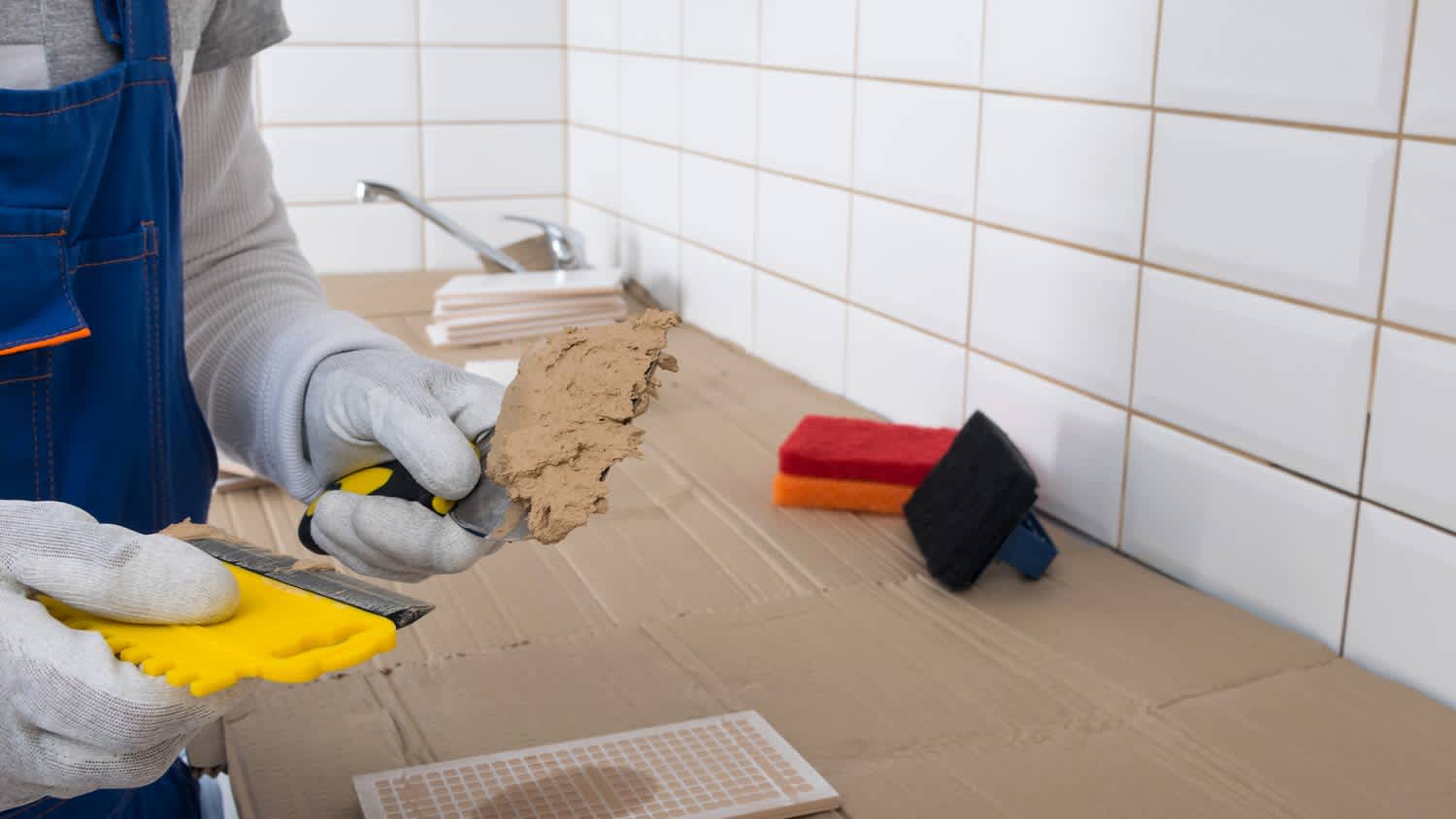 None man applying grout to wall tiles
