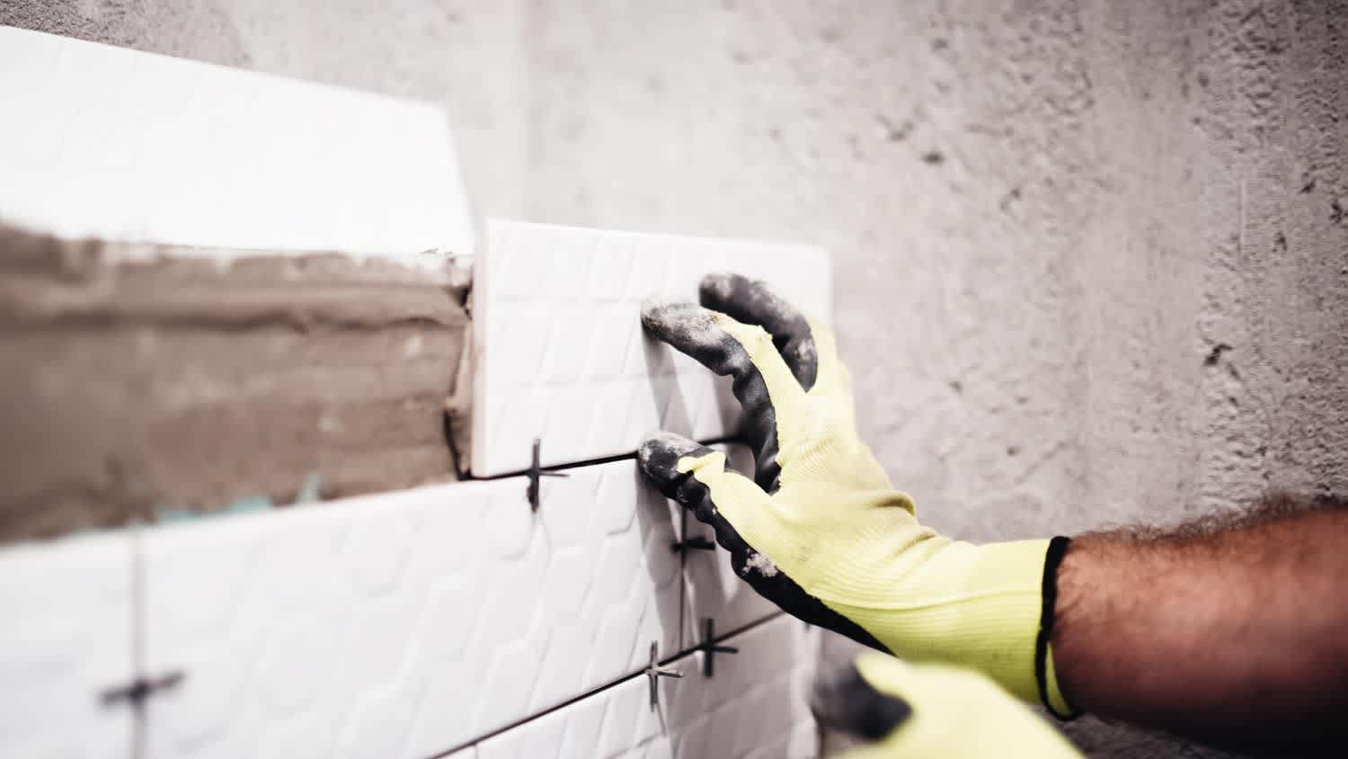 None Close-up of a man’s hand putting tiles on wall