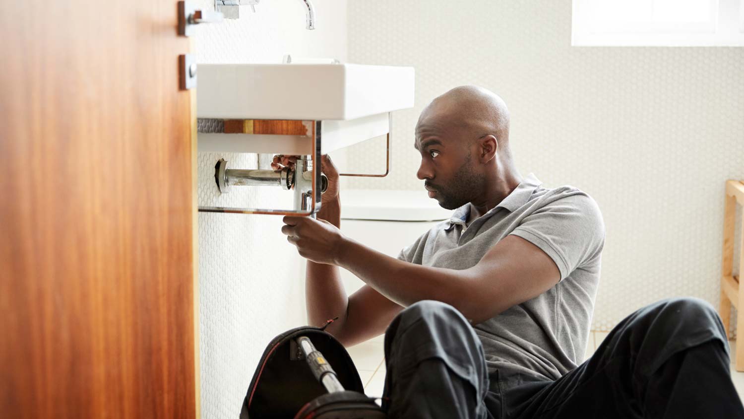 None A plumber installing a small sink